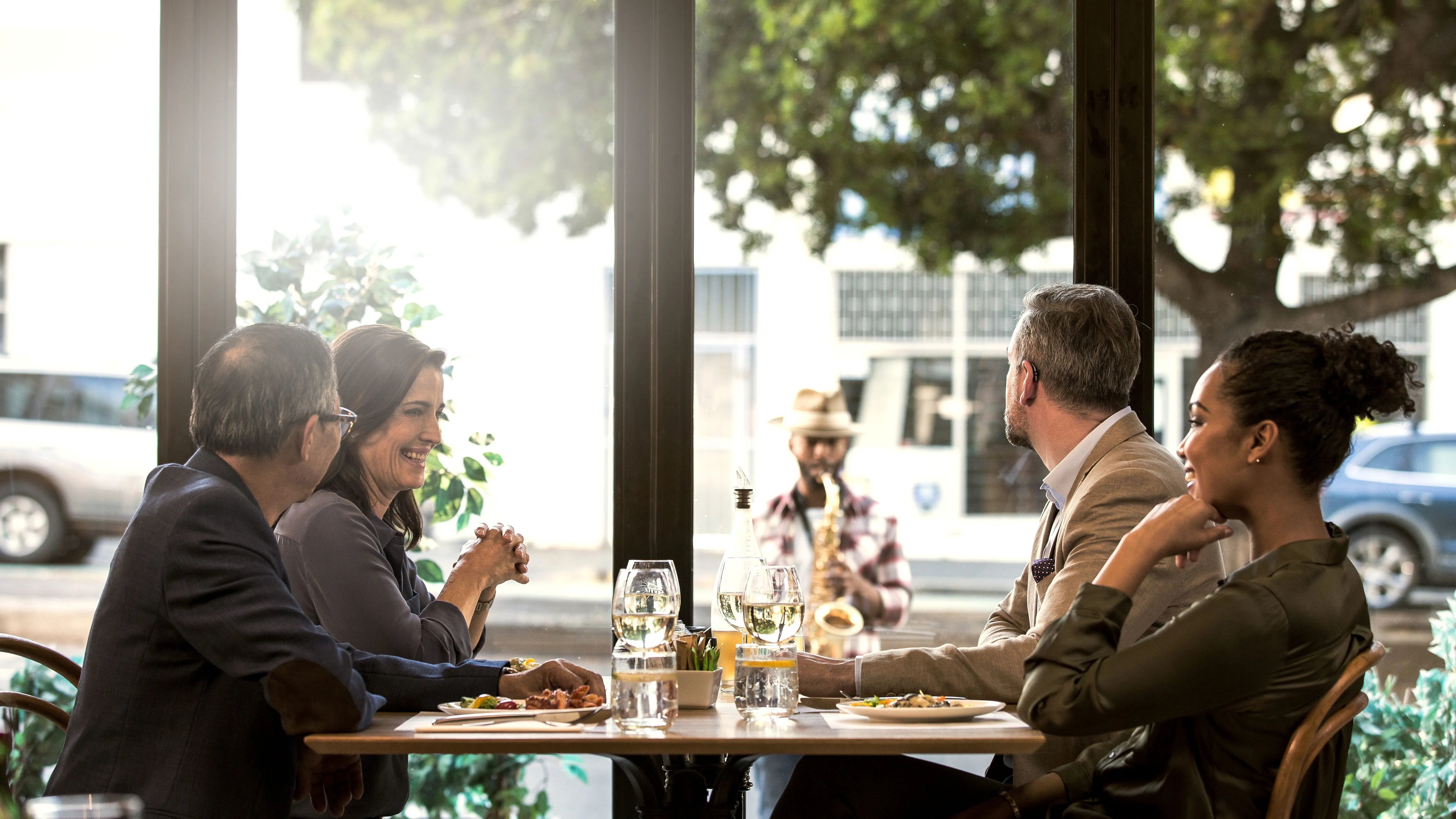 Amigos num café, onde as conversas são difíceis de acompanhar devido a perda auditiva.