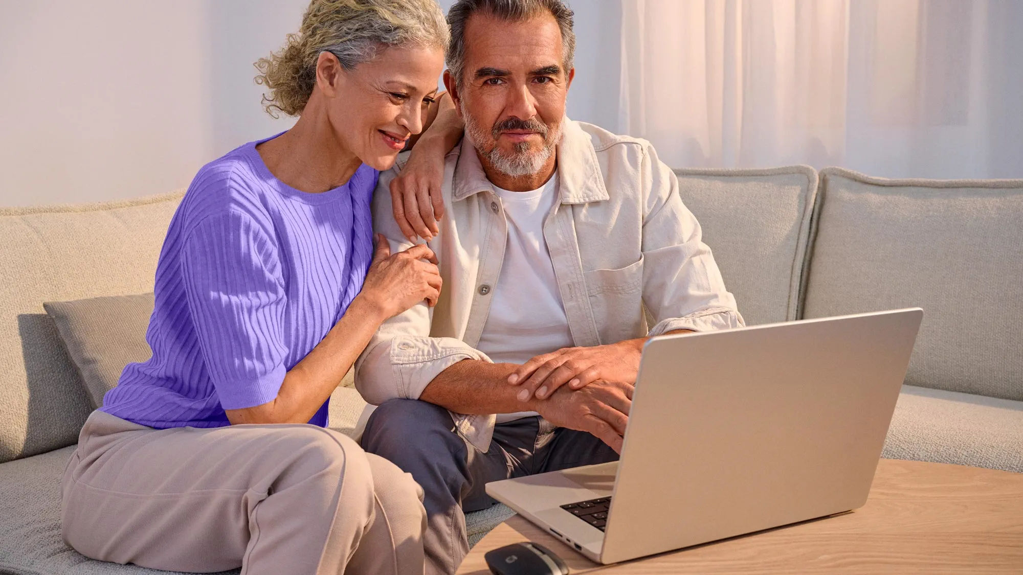 Casal confiante a usar tecnologia, destacando melhoria auditiva.