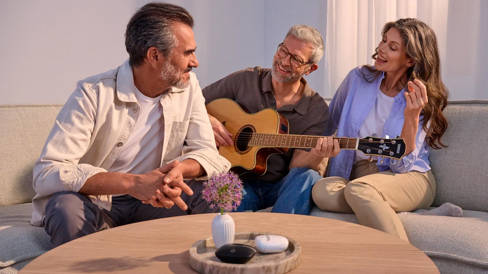 Reunião casual de amigos em torno de uma guitarra, a usar aparelhos auditivos.