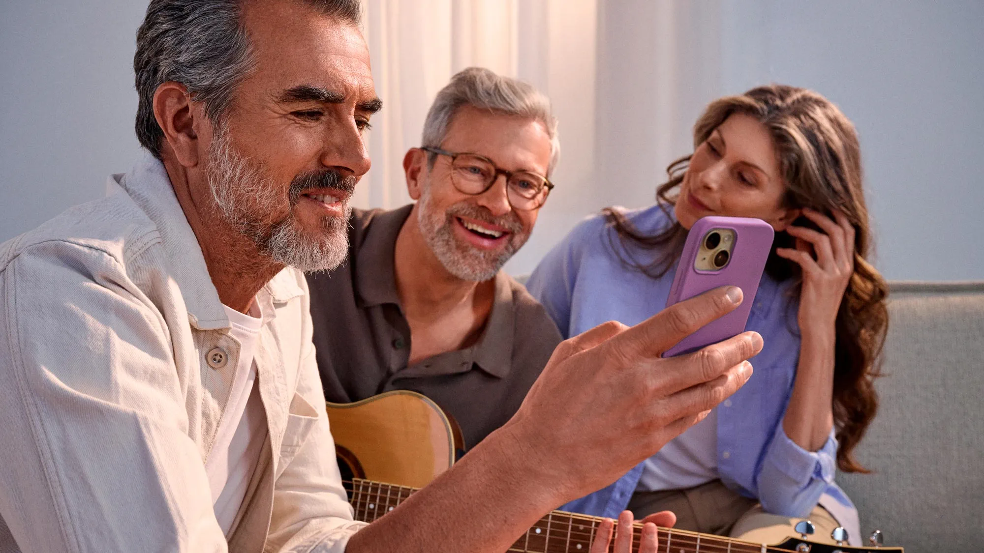 Grupo casual de amigos a olhar para um telefone, a celebrar a melhoria auditiva.