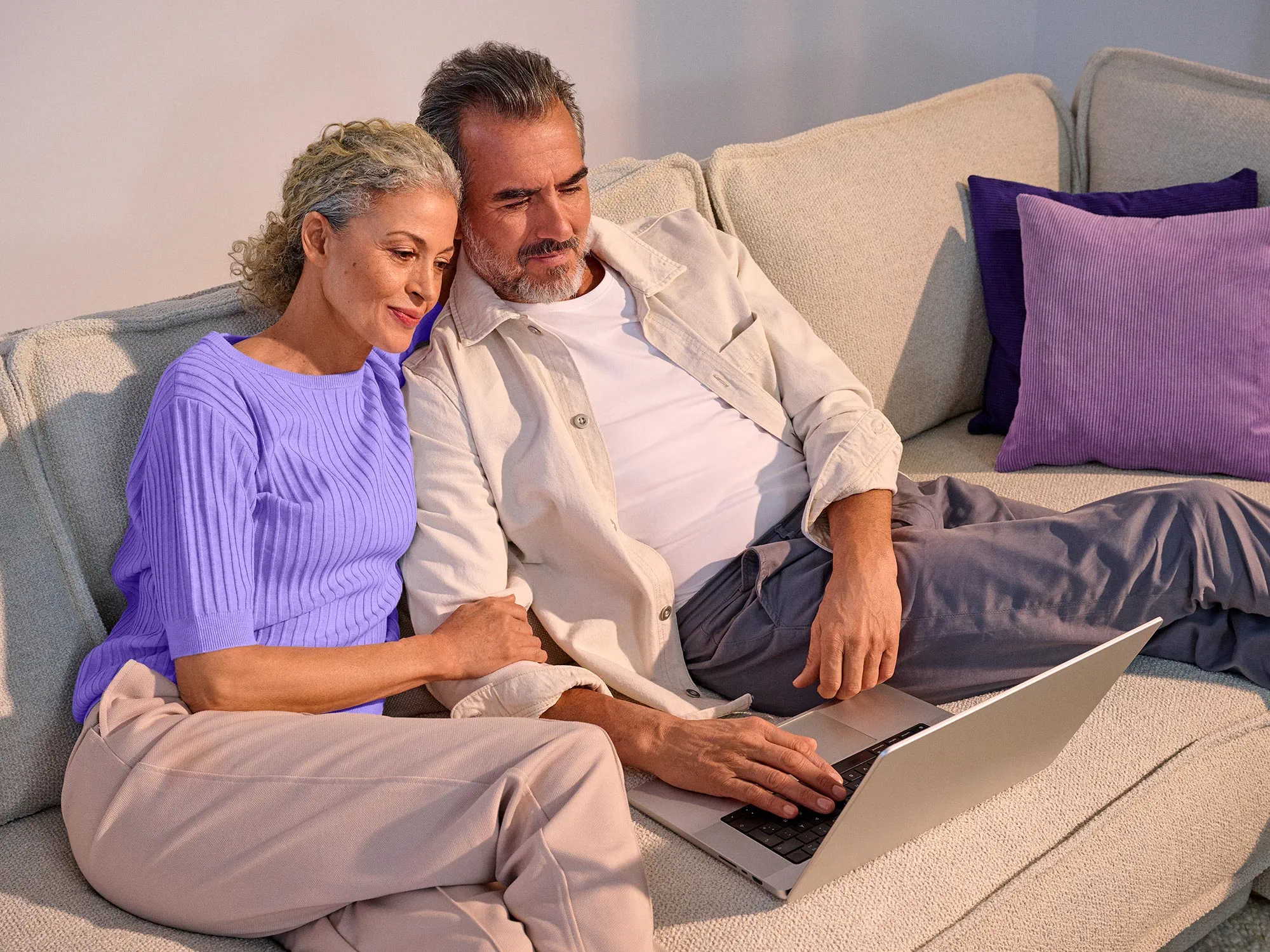 Casal a parecer confortável, a usar tecnologia com os seus aparelhos auditivos.