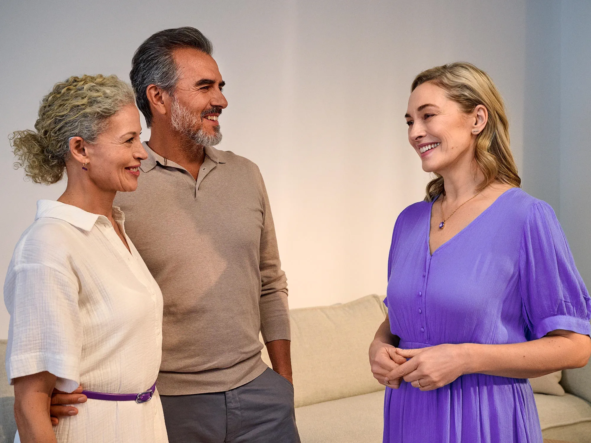 Casal a conversar com um amigo, a desfrutar da conversa graças à melhoria auditiva.