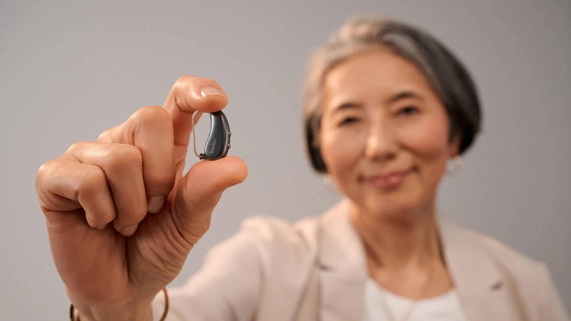 Woman holding Signia Pure between her fingers to show how tiny it is