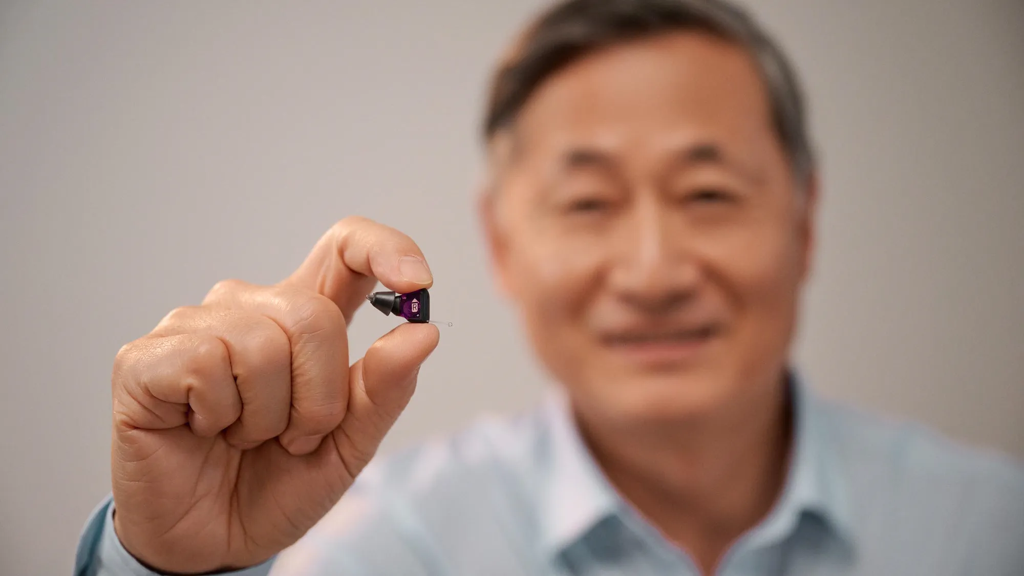 Man holding Signia Silk between his fingers to show how tiny it is