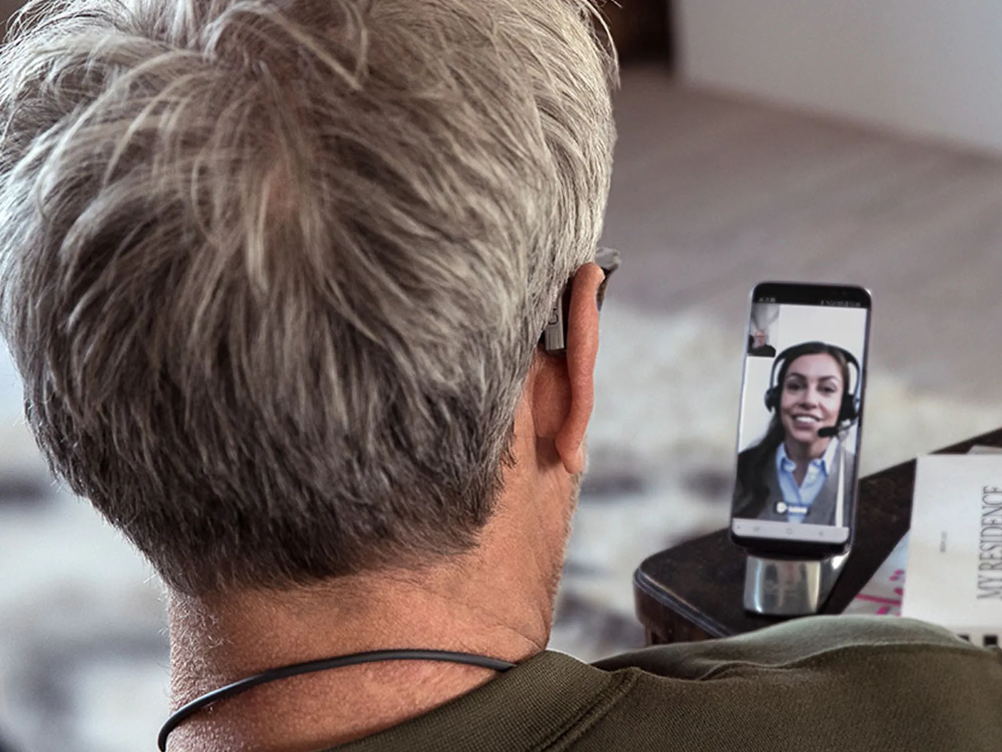Mulher a usar aparelhos auditivos e a entrar em contacto com o seu audiologista através do Widex Remote Care.
