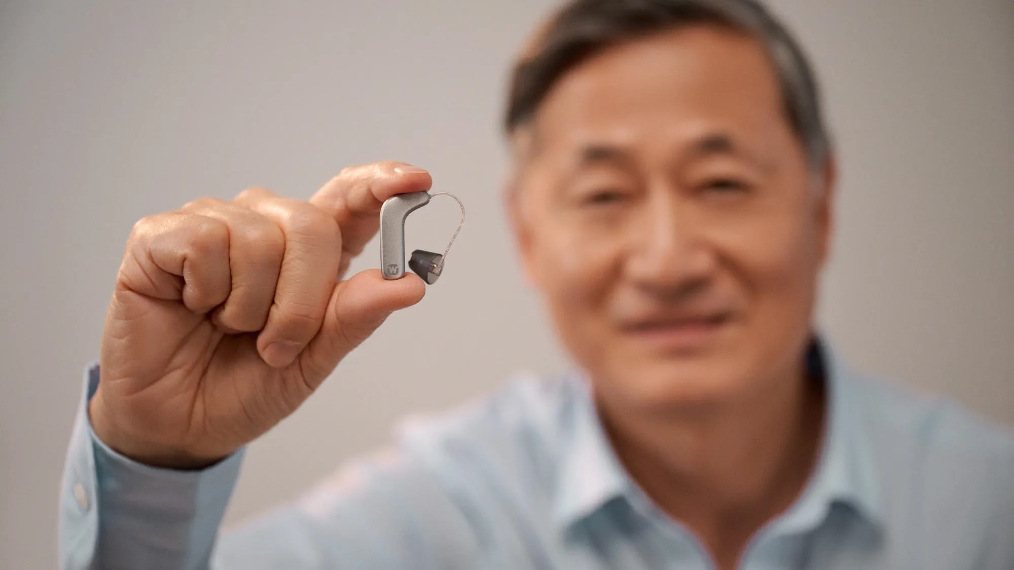 man-pinching-widex-smart-ric-hearing-aid-fingers-16x9